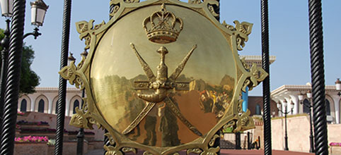 Omanisches Flaggen-Symbol auf einem goldenen Schild vor einem Palast