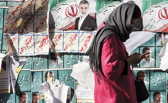 Iranerin geht an einer mit iranischen Wahlplakaten beklebten Wand vorbei