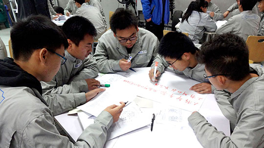 several chinese people sitting around a table preparing a poster