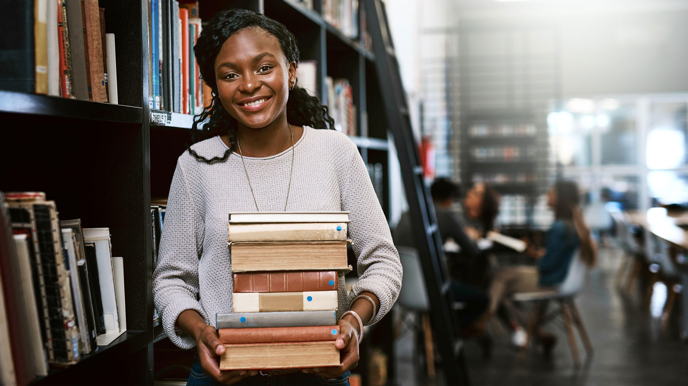 junge Afrikanerin trägt mehrere Bücher