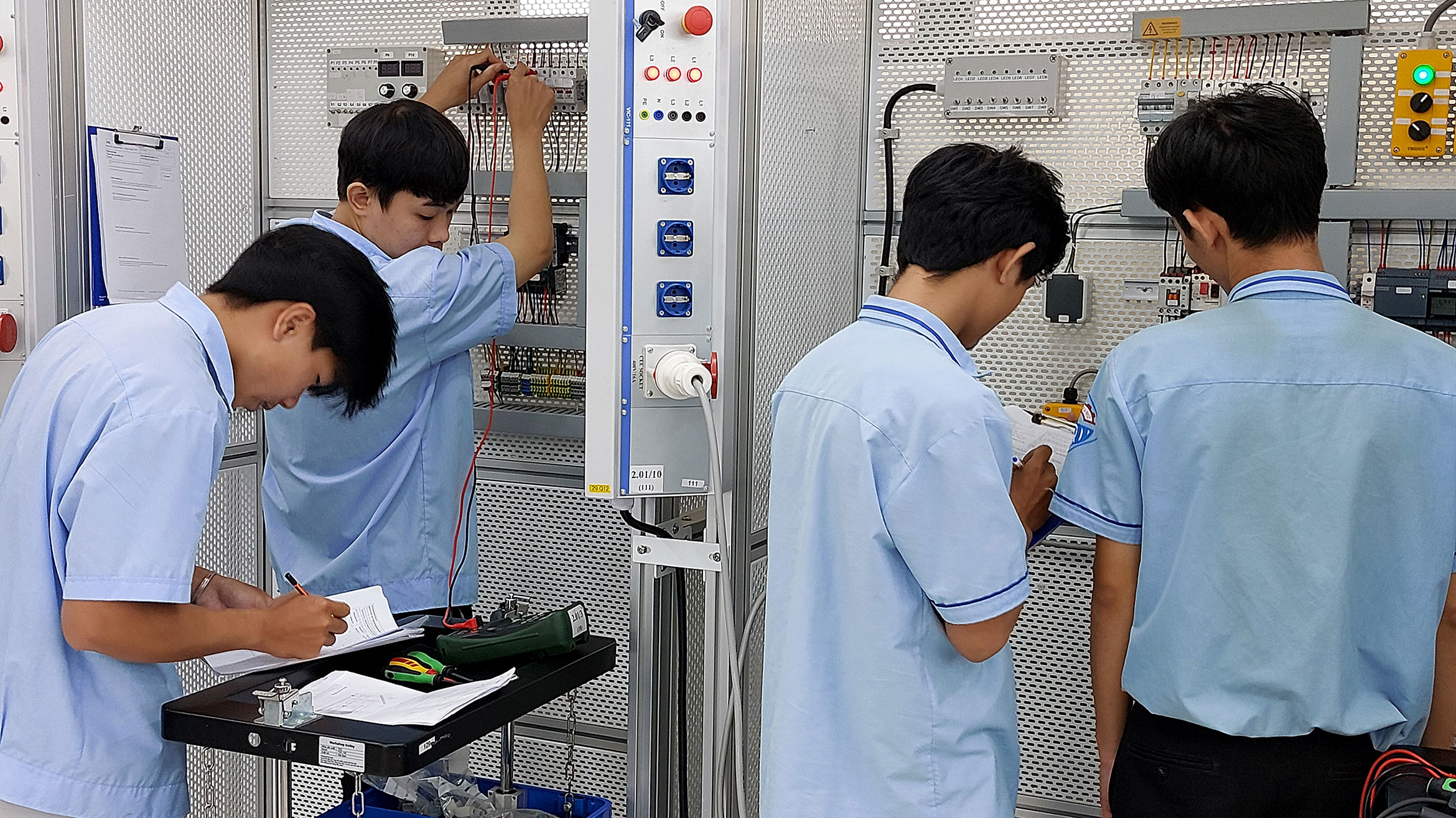 vier junge vietnamesische Männer arbeiten an Schaltwänden