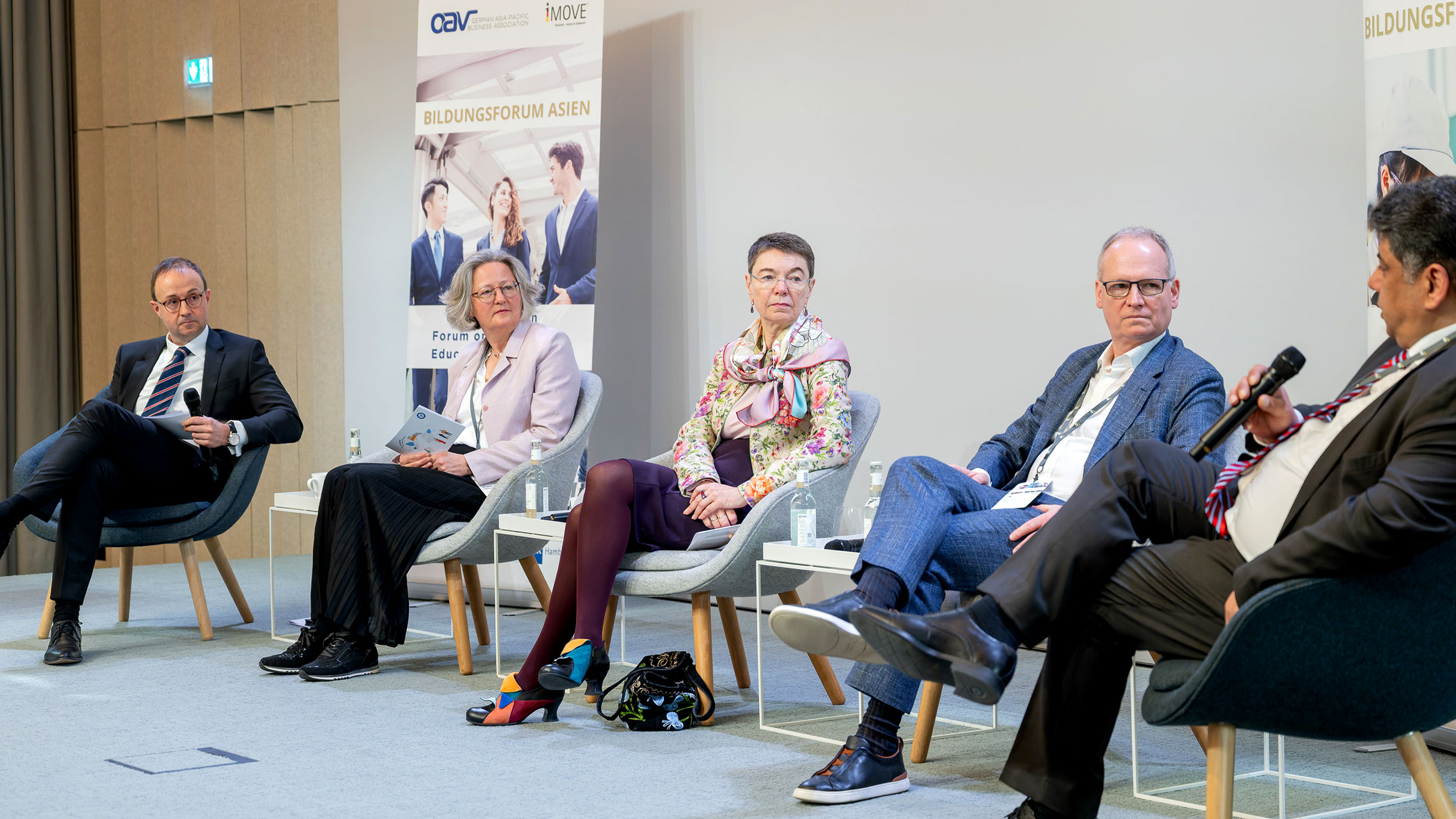 Blick auf Moderator und Panelisten auf dem Podium