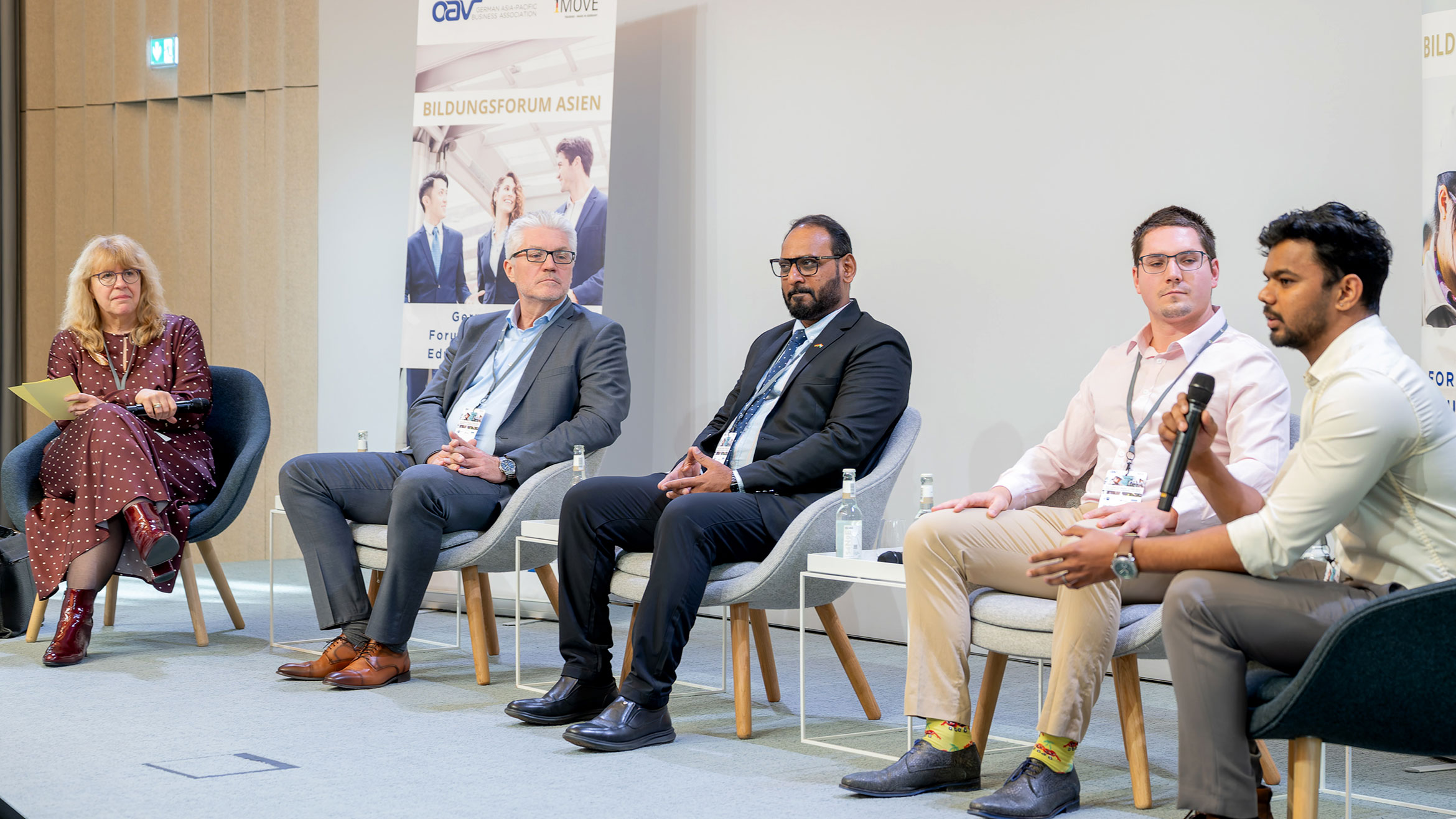 Moderatorin und vier Sprecher sitzen auf dem Podium