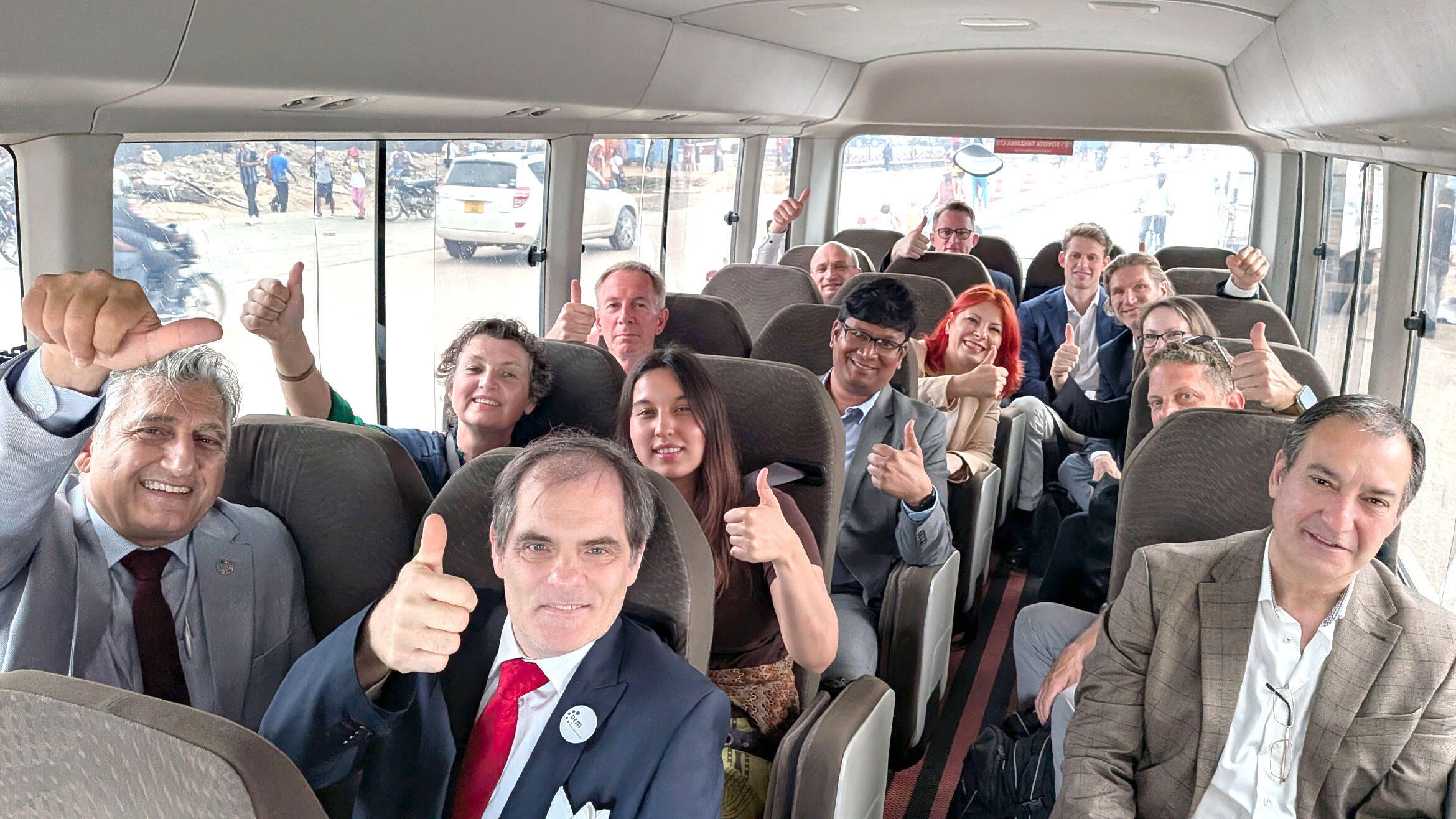 Delegation sitzt im Bus und alle strecken den Daumen in die Luft