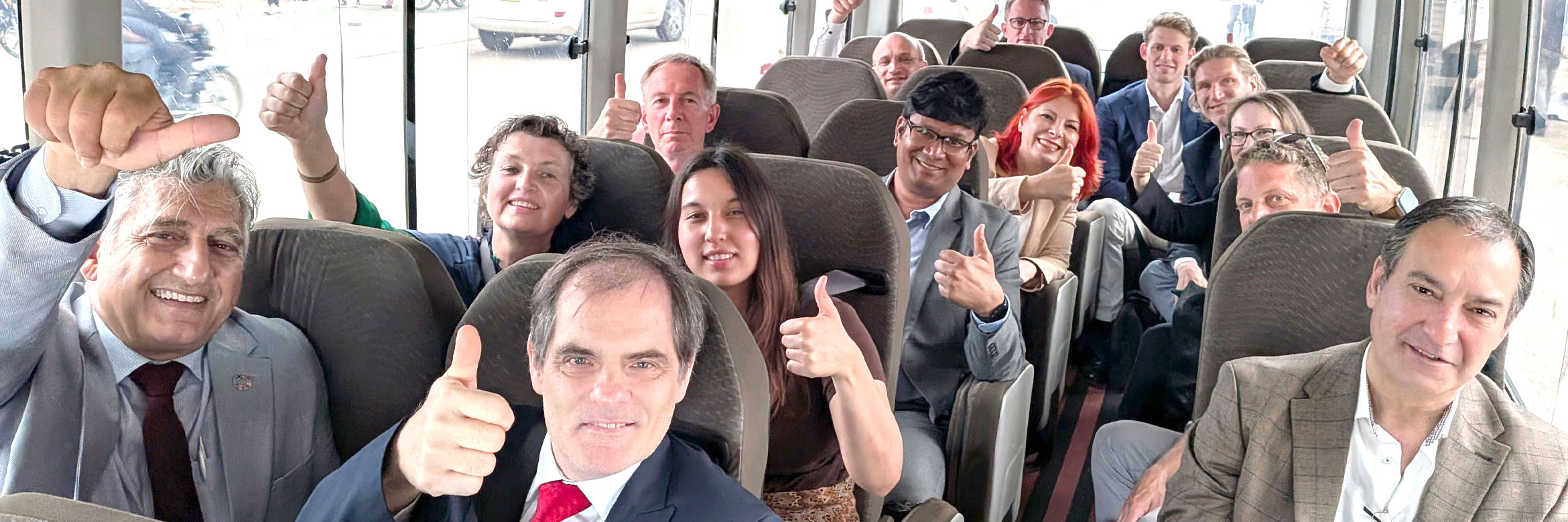 Delegationsteilnehmende sitzen in Bus und zeigen Daumen hoch