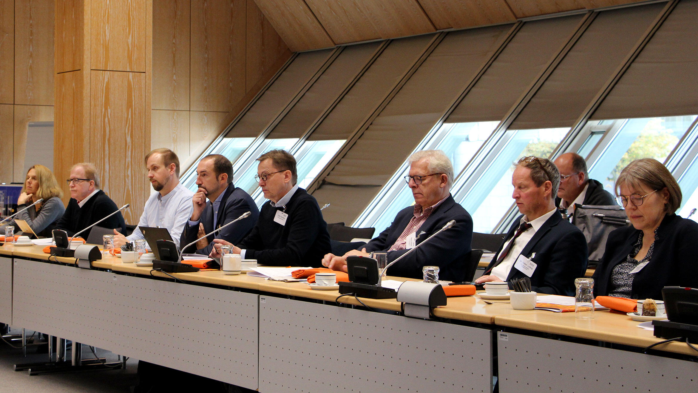 Blick auf eine Sitzreihe mit sieben Teilnehmern und zwei Teilnehmerinnen