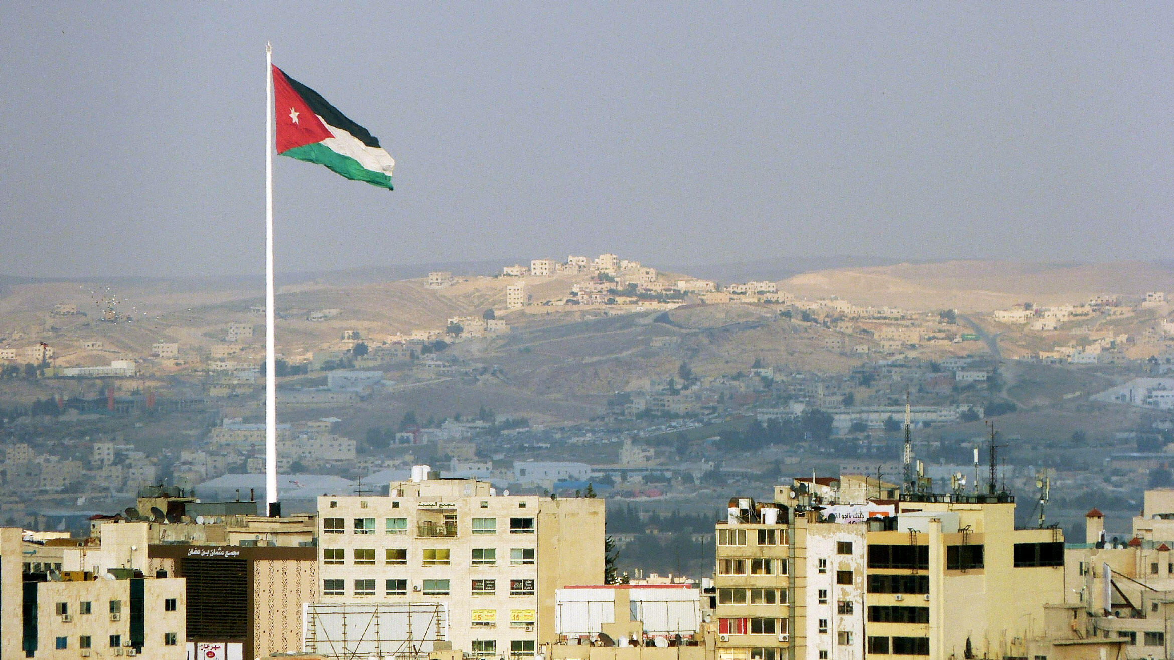 Blick auf Amman mit wehender Nationalflagge im Vordergrund