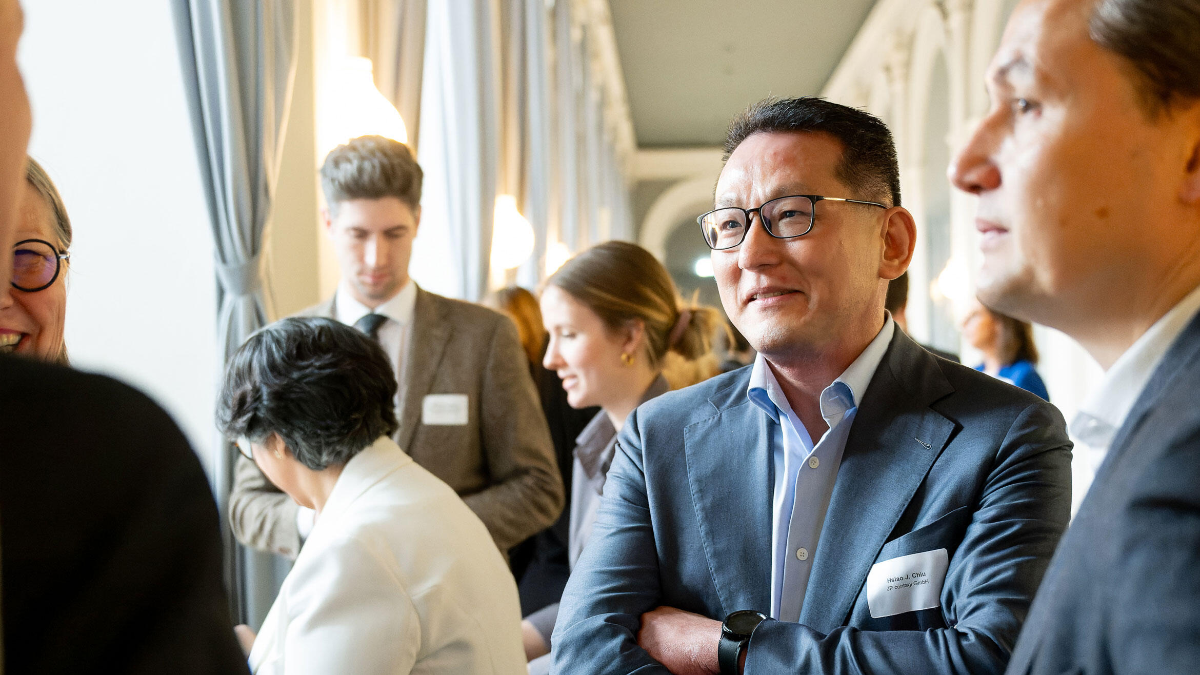 zwei Asiaten schauen im Gespräch auf eine weitere Person, die nicht im Bild ist