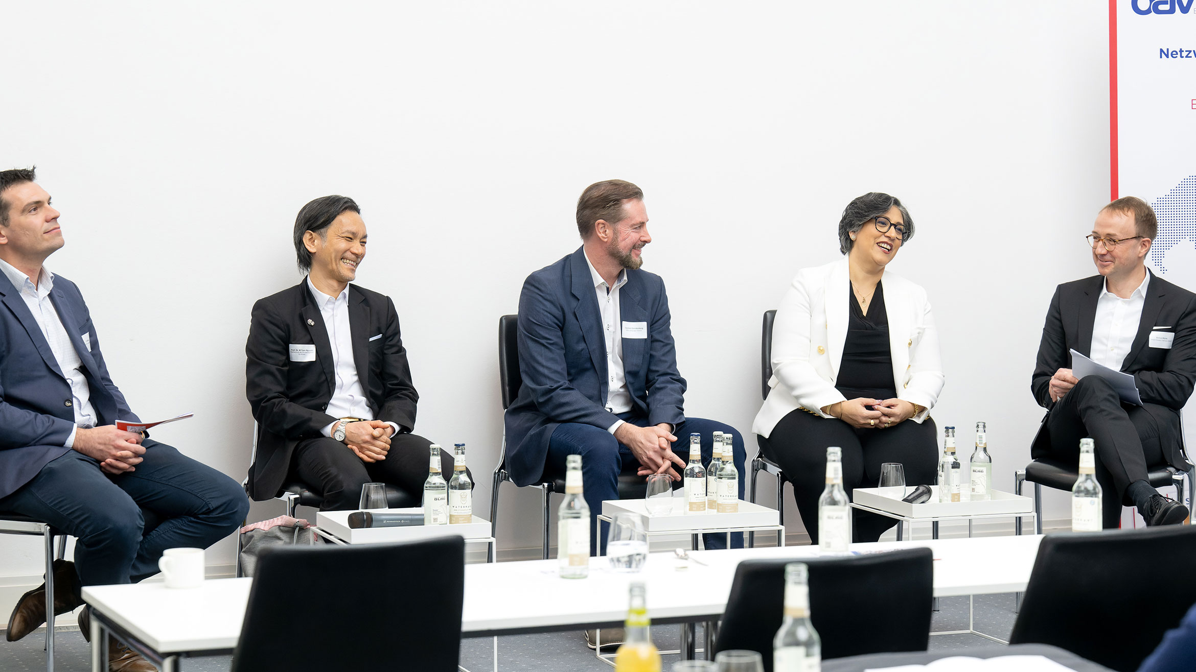 Moderator und vier Panelisten sitzen auf dem Podium