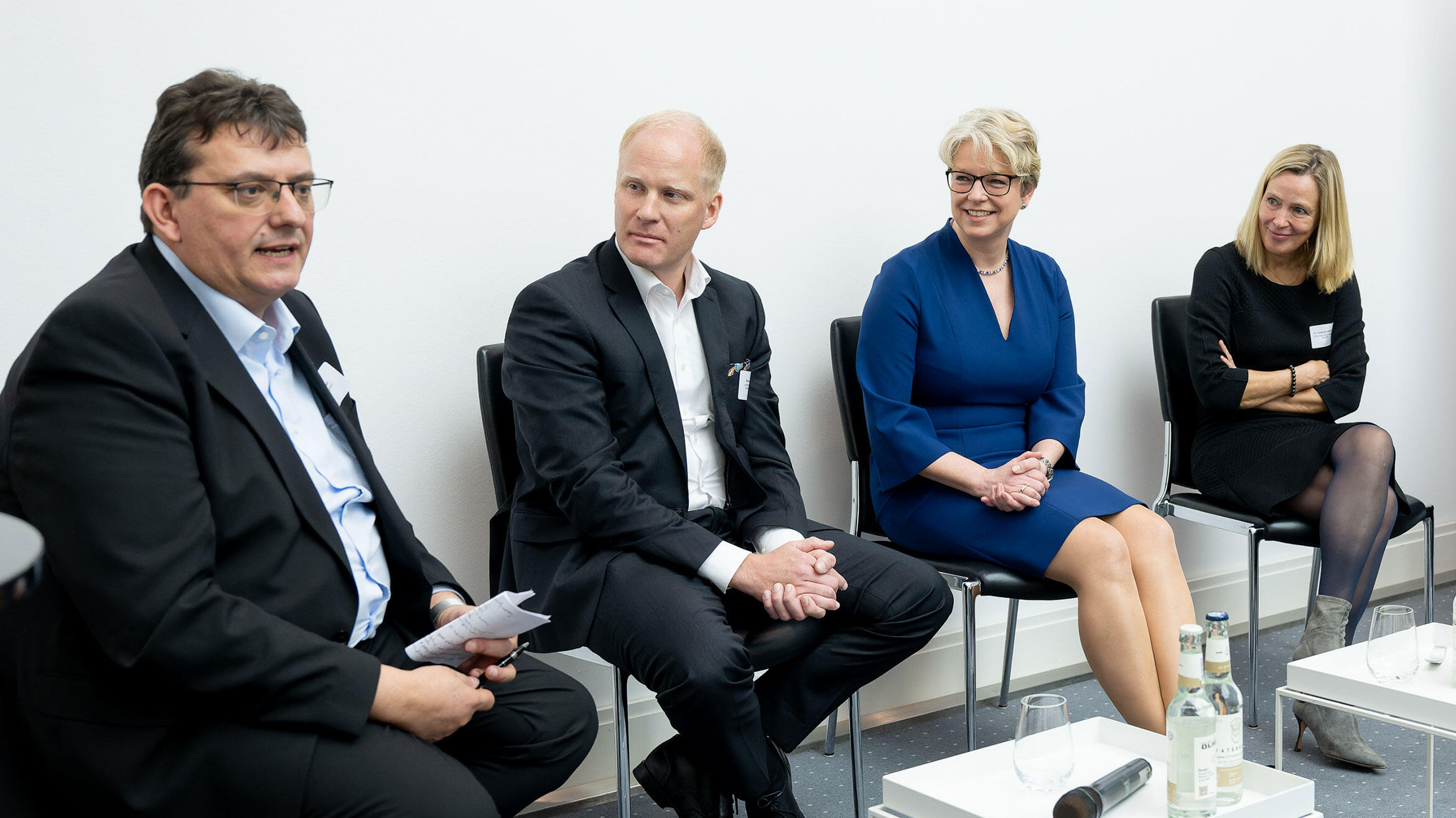 Sprecher sitzen beim ersten Panel auf dem Podium