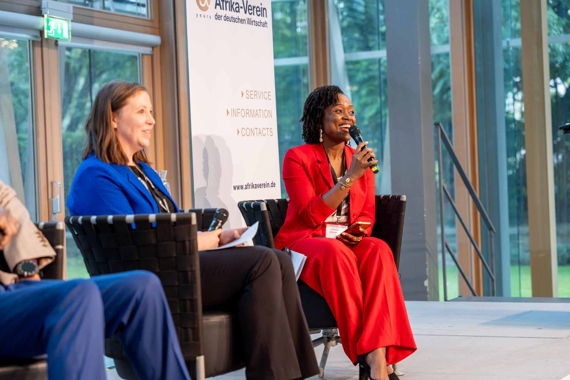 Katarina Kunert mit Sandra Gouadjio, EUROCHAM Kamerun sitzen auf dem Podium, Gouadijo spricht ins Mikrofon