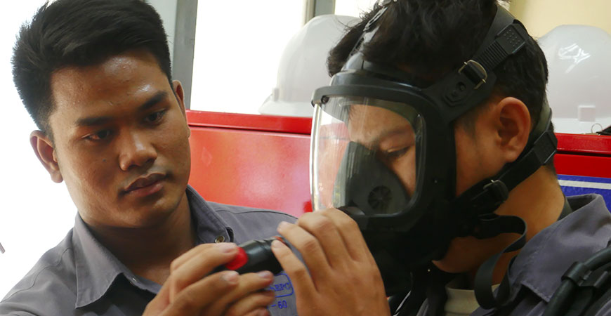 ein Thai hilft einem anderen beim Anziehen einer Gasmaske