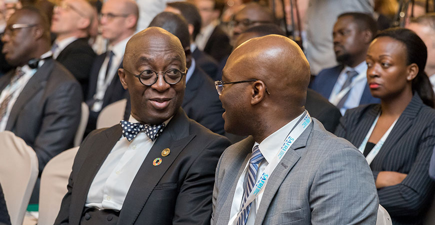 Nahaufnahme von zwei afrikanischen Teilnehmern des Wirtschaftsgipfels, die im Auditorium sitzen und miteinander sprechen