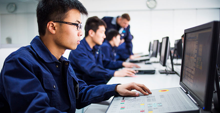 mehrere junge Chinesen in Blaumännern arbeiten an Computern