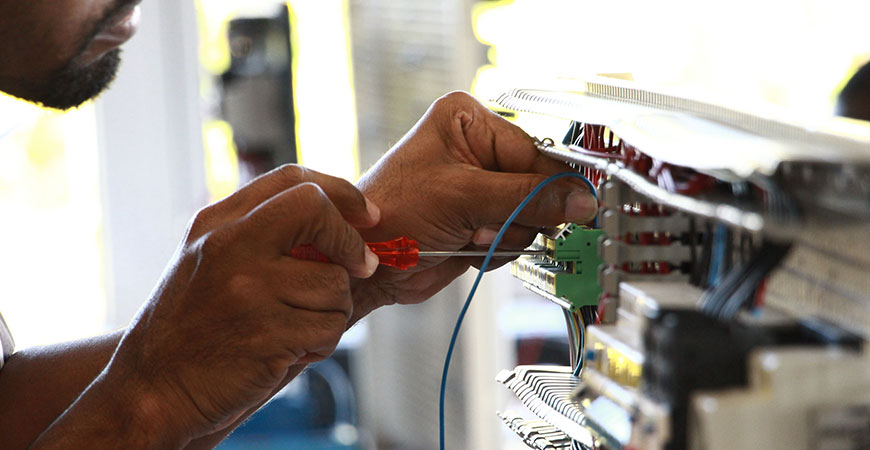 Detailaufnahme von Händen, die an elektrischer Schalttafel arbeiten