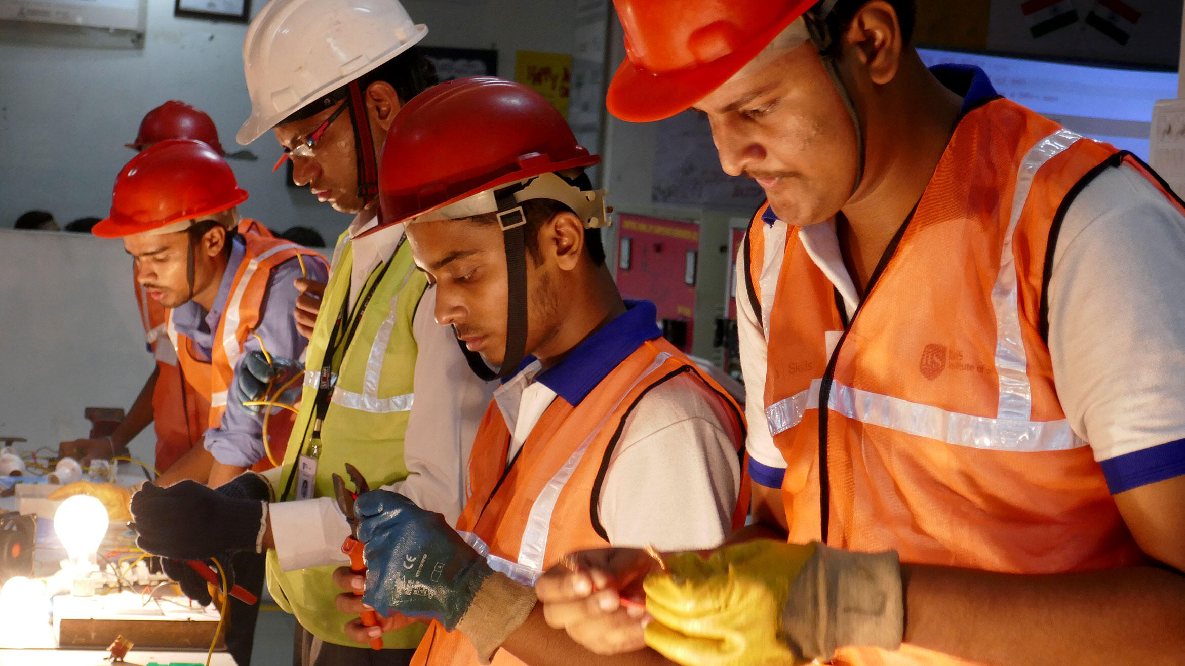 four Indian men in work clothes working in a workshop