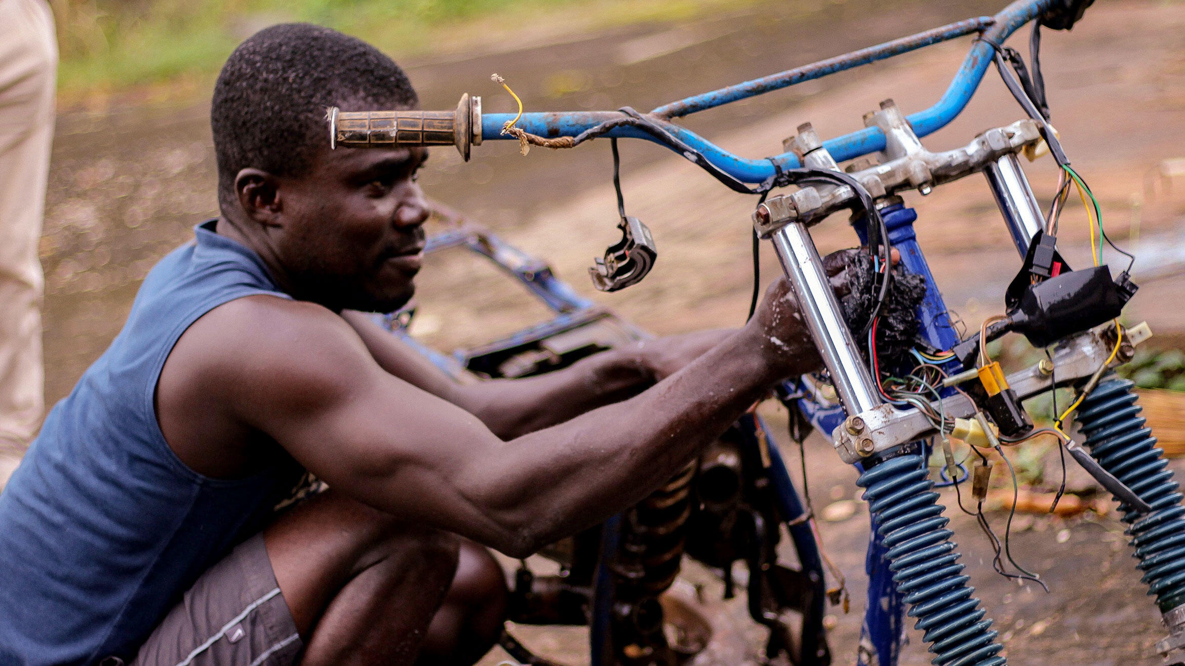mutmaßlich afrikanischer Mann repariert ein Motorrad