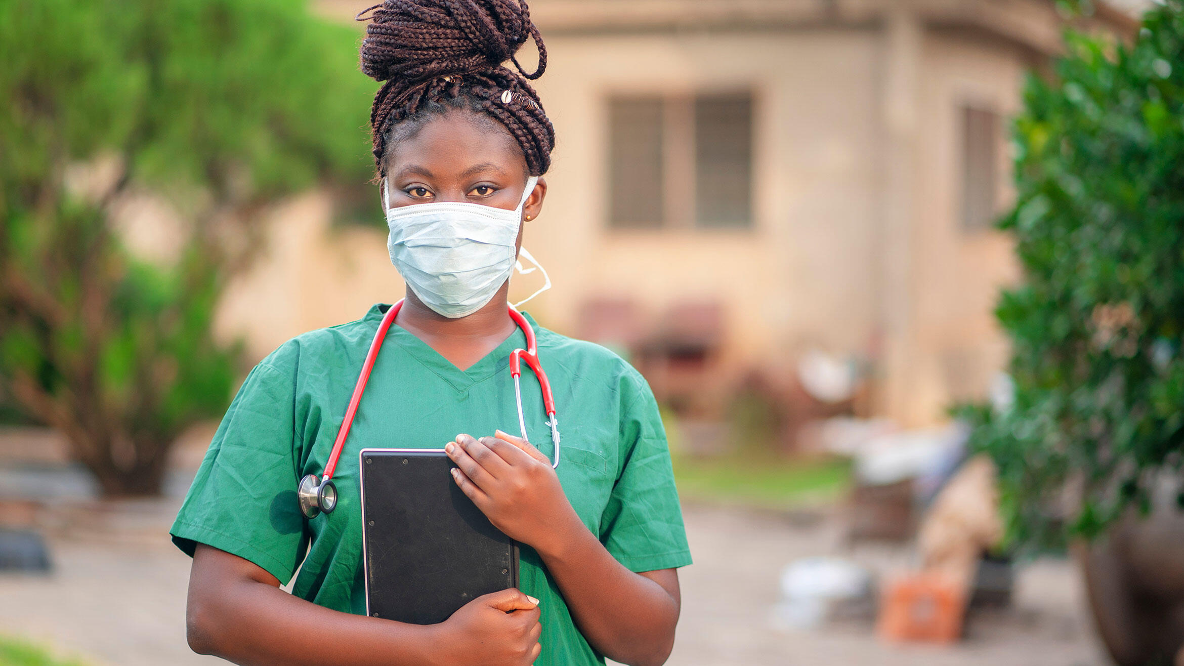 Ghanain aus dem Gesundheitssektor in Arbeitskleidung mit Mund-Naseschutz