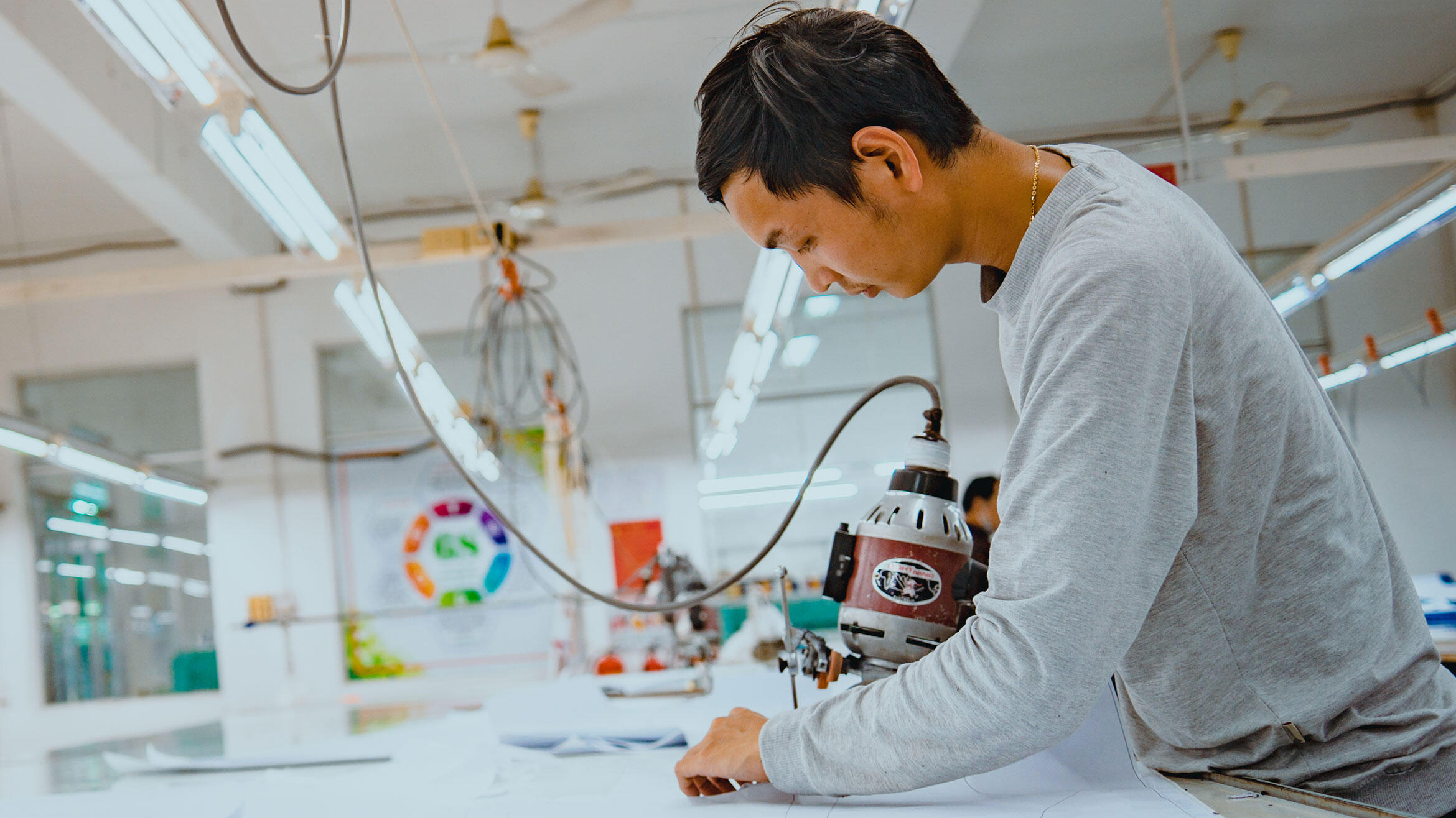 Vietnamese arbeitet mit Schneidemaschine an Schnitttisch