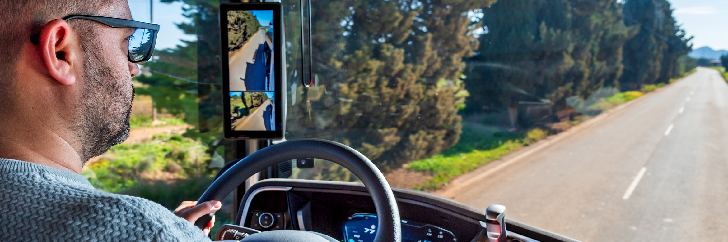 Lkw-Fahrer, aus der Perspektive der Fahrerkabine fotografiert, fährt auf einer zweispurigen Straße, mit einer Spur für jede Fahrtrichtung, die durch die Landschaft führt 