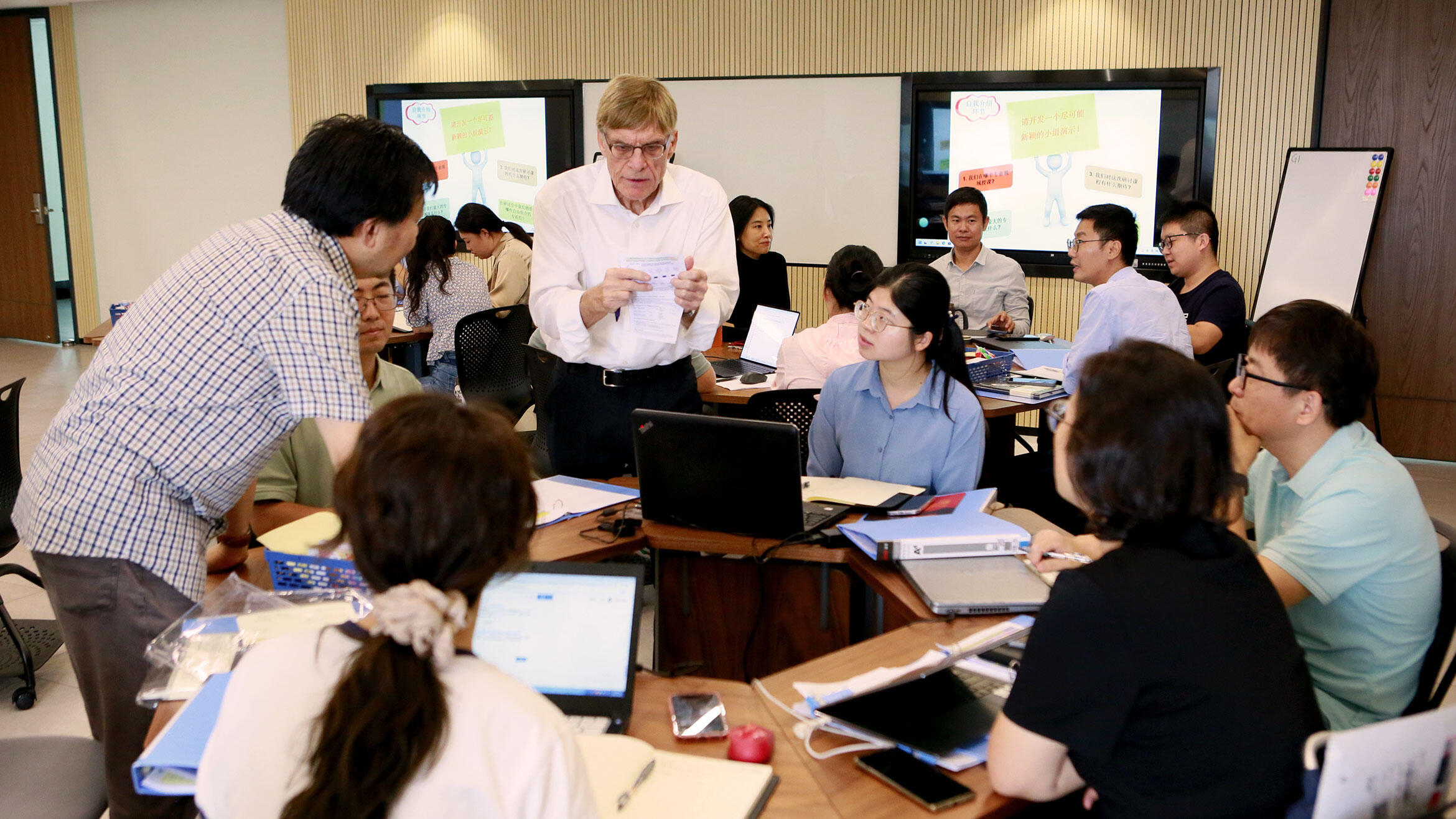 chinesische Trainer sitzen um einen Tisch herum und sprechen mit Kursleiter