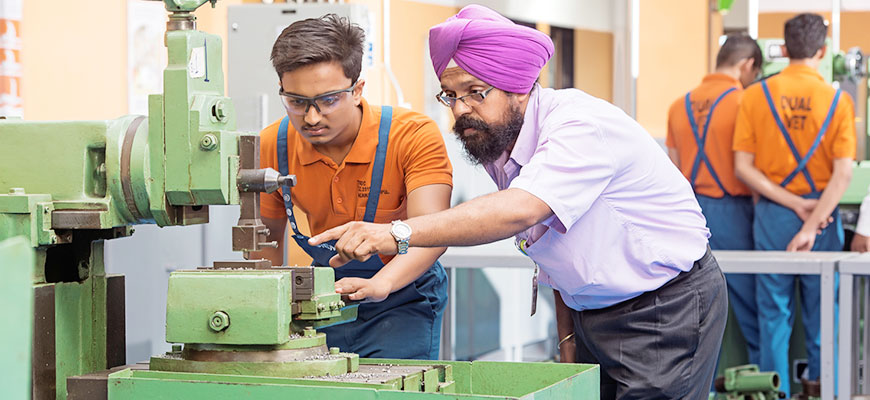 Indischer Ausbilder und Auszubildender arbeiten an einer Fräsmaschine