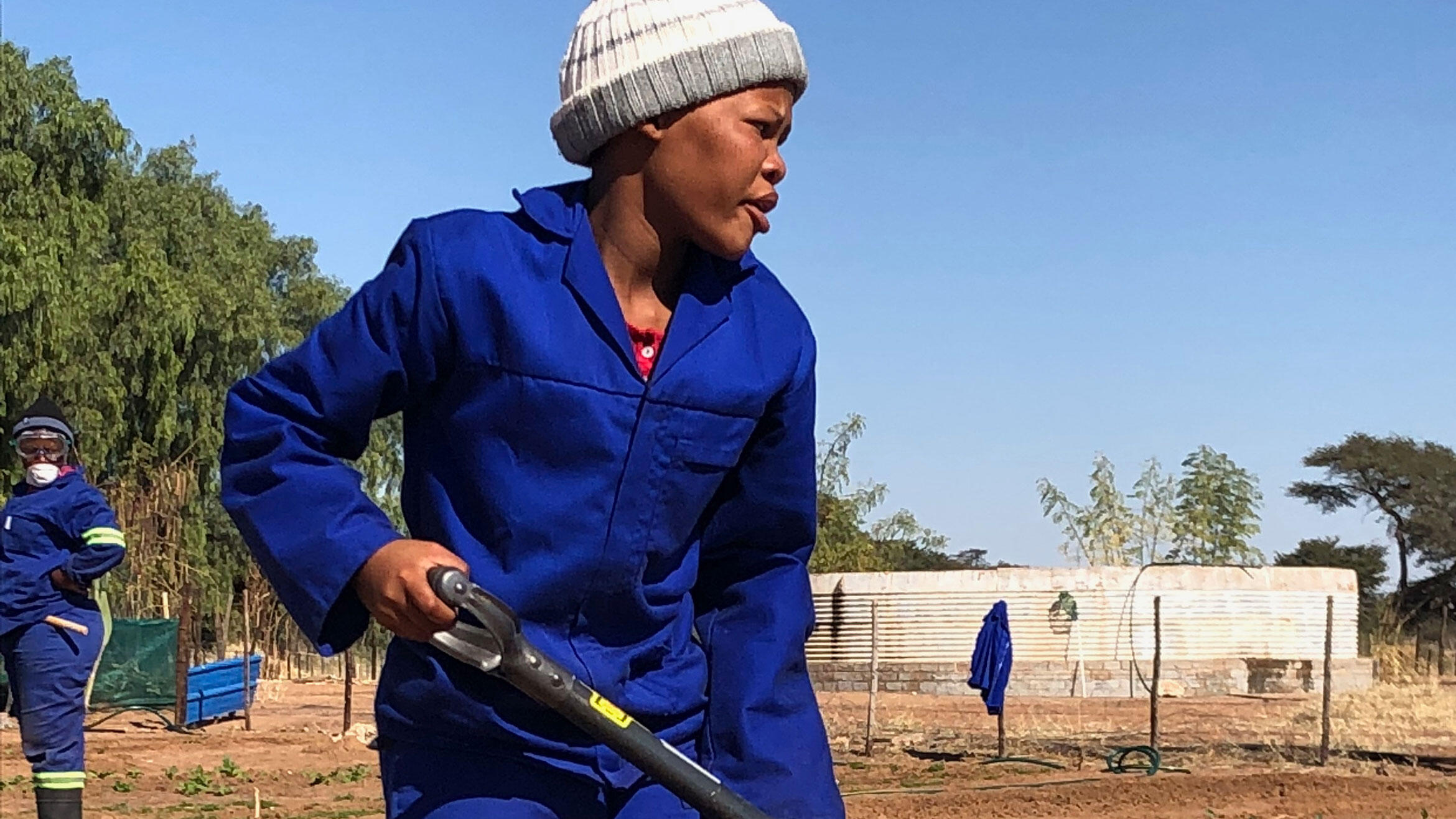 namibische Frau in Arbeitskleidung arbeitet mit einem Spaten