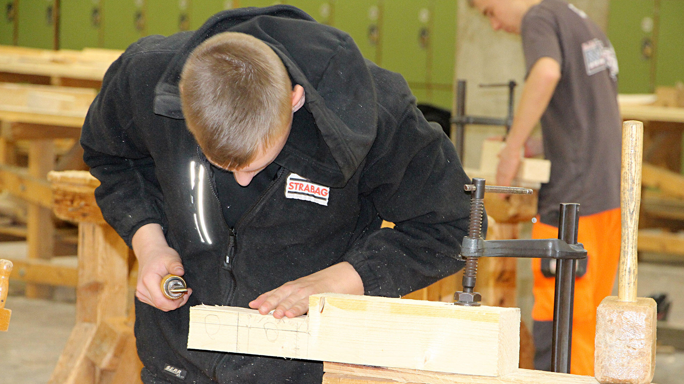 Auszubildender arbeitet an Holzbalken