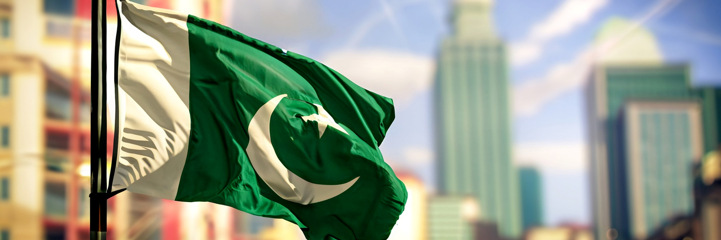 Nationalflagge Pakistans weht vor blassem Hintergrund von hohen städtischen Gebäuden
