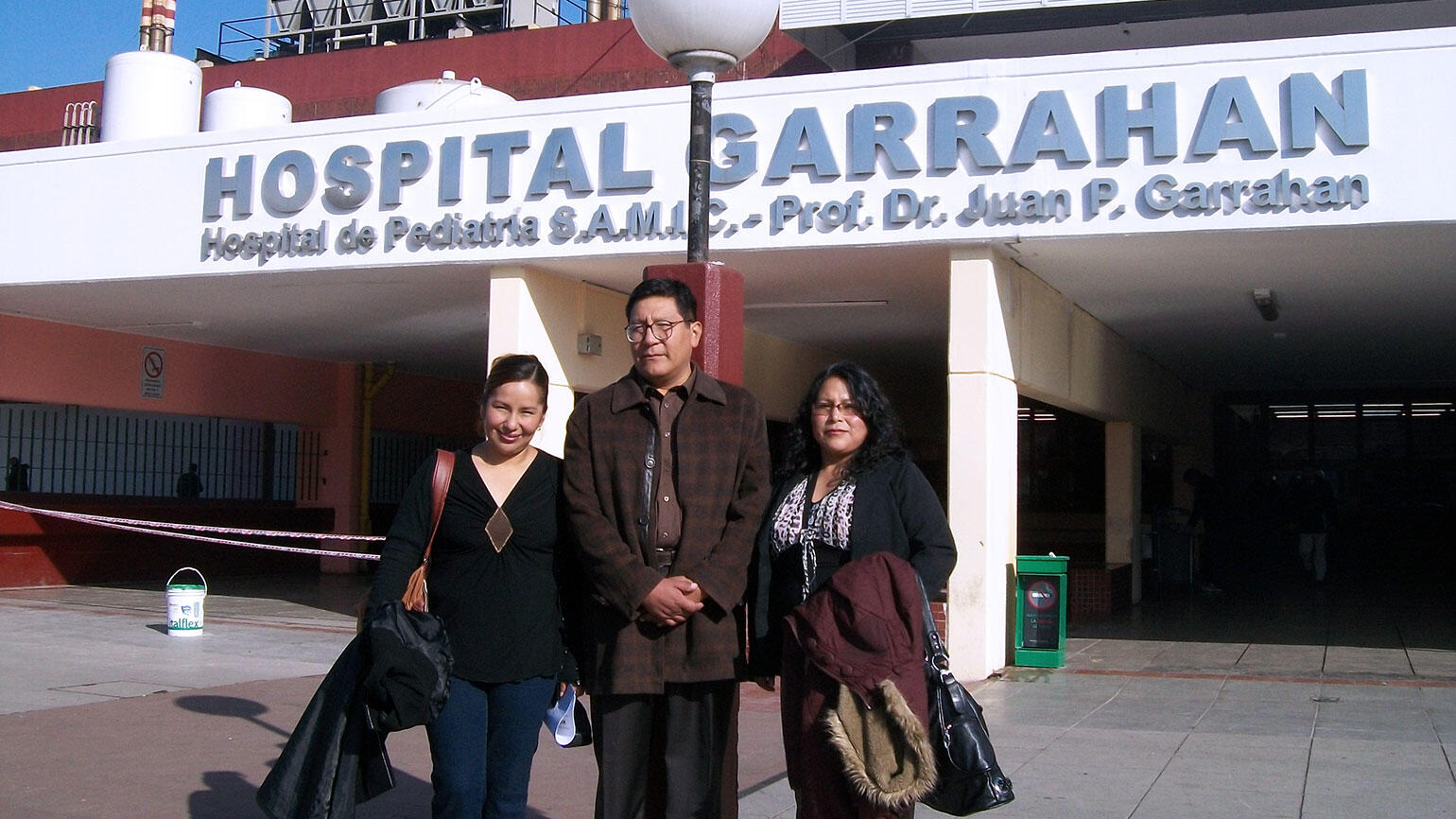 3 Personen vor einem Krankenhaus in Bolivien