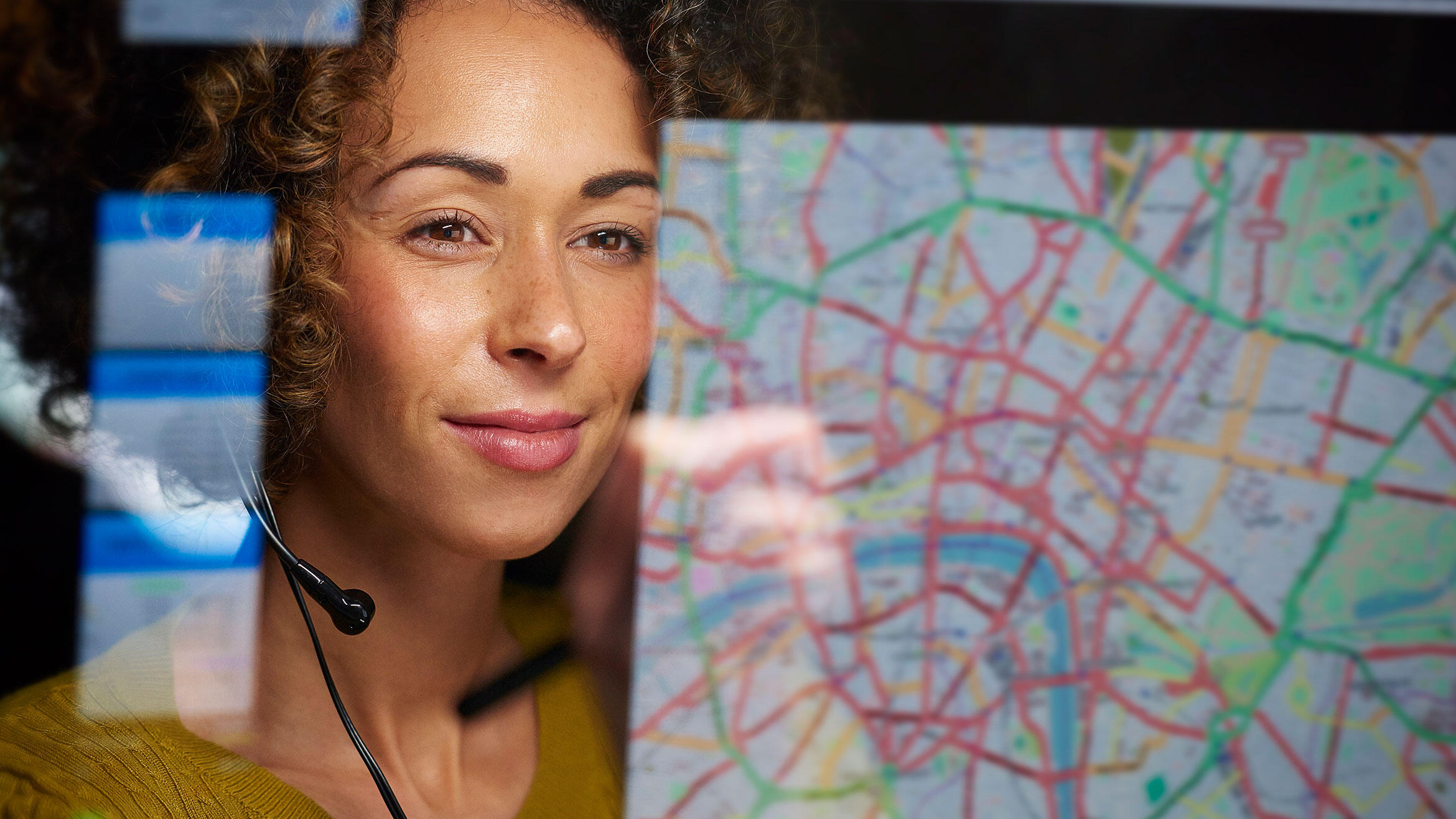 spiegelnde Straßenkarte, dahinter das Gesicht einer Europäerin mit einem Headset