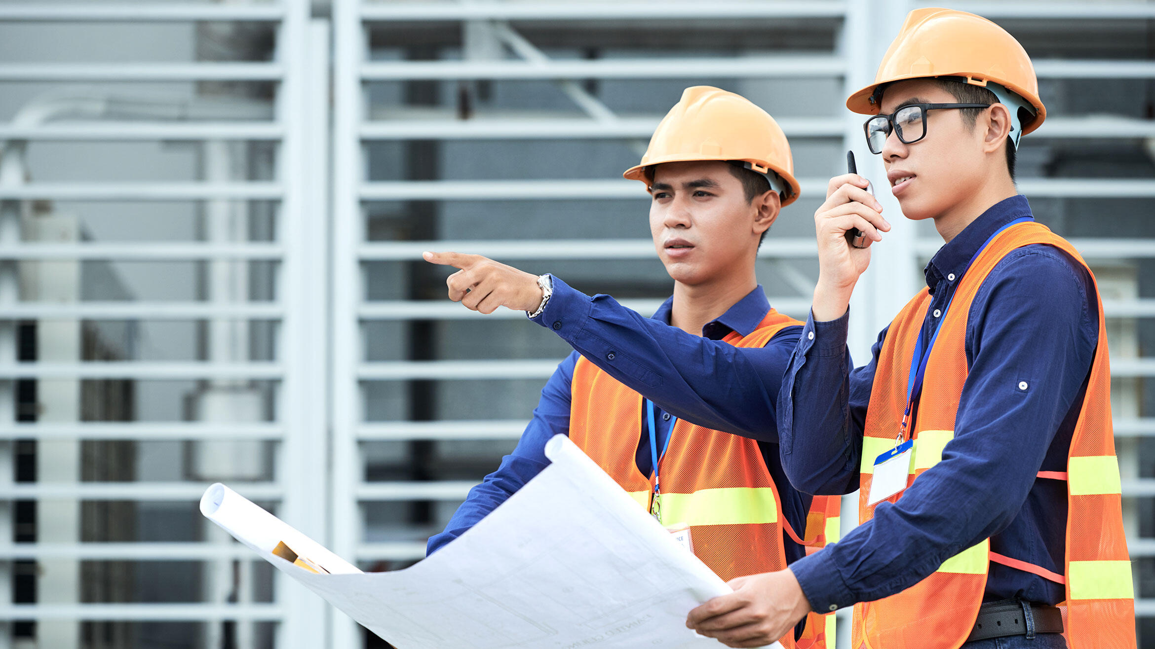 zwei mutmaßlich vietnamesische junge Männer in Sicherheitskleidung auf einer Baustelle