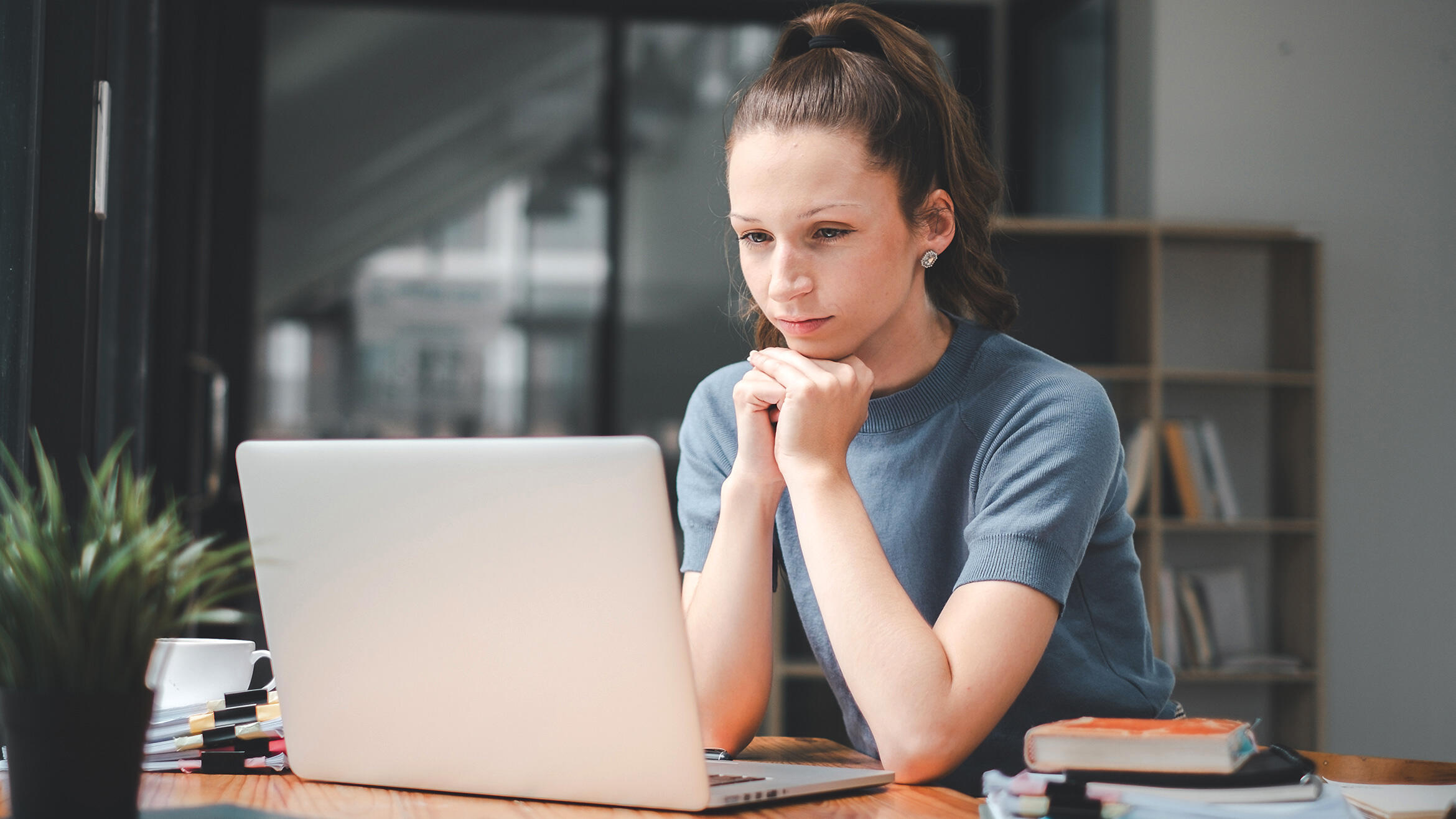 Frau schaut aufmerksam auf Bildschirm eines Laptops