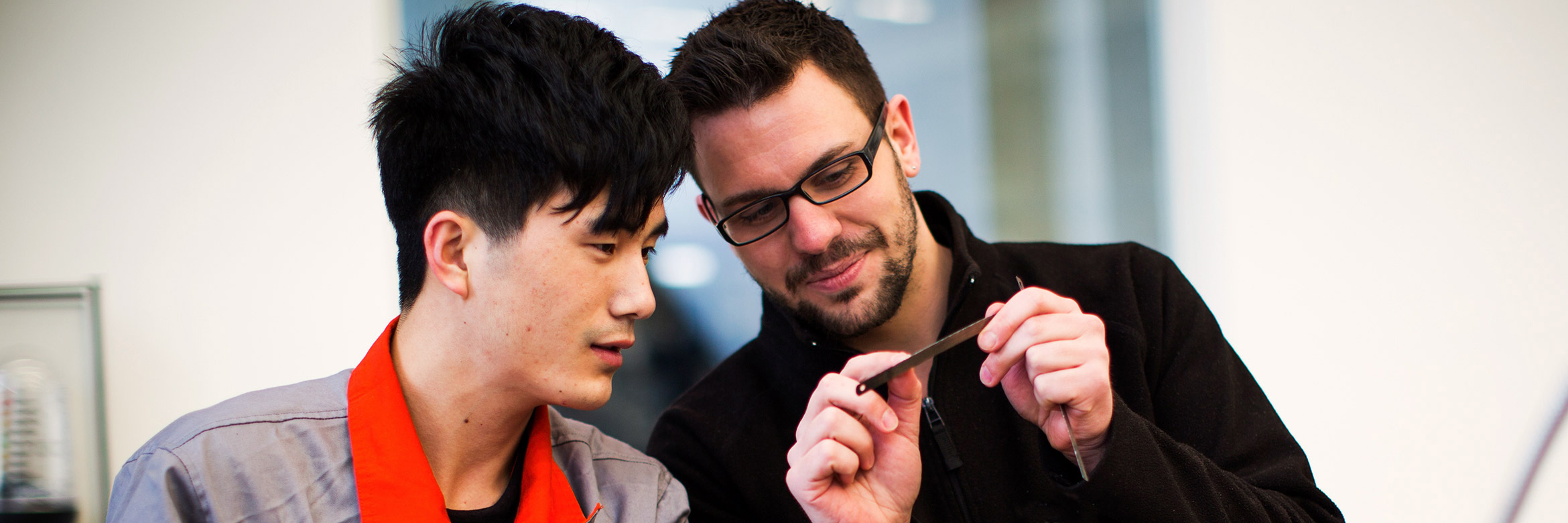 zwei Männer in Arbeitskleidung sehen sich ein Sägeblatt an