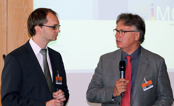 zwei Referenten stehen vor den Teilnehmern und sprechen miteinander