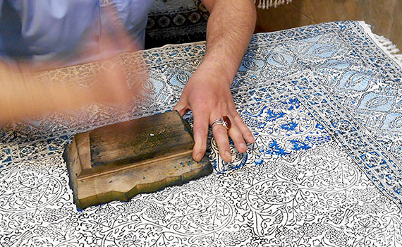 Detailansicht: handwerkliches Färben eines Teppichs mit Holzstempel