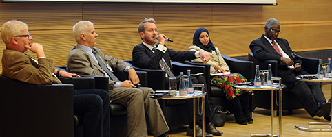 Teilnehmerin und Teilnehmer sowie Leiter der Session auf dem Podium