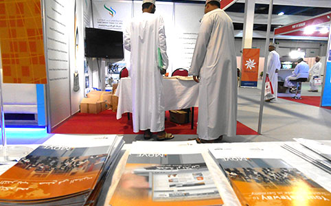 Blick über iMOVE-Flyer auf zwei omanische Besucher