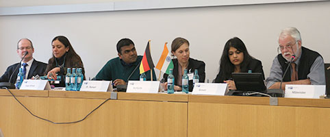 Sprecherinnen und Sprecher sitzen auf Podium