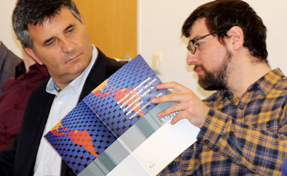 zwei Delegationsteilnehmer aus Chile schauen in die iMOVE-Publikation mit Erfolgsgeschichten aus Lateinamerika