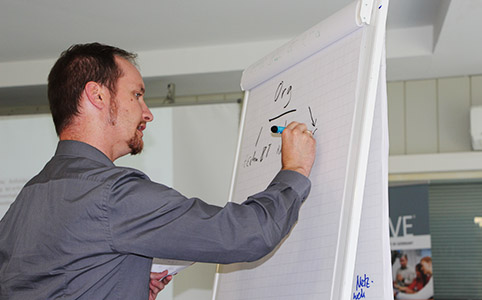 Nahaufnahme: Teilnehmer schreibt an Flipchart