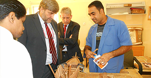 arabische und deutsche Männer betrachten ein Schiffsmodell aus Holz
