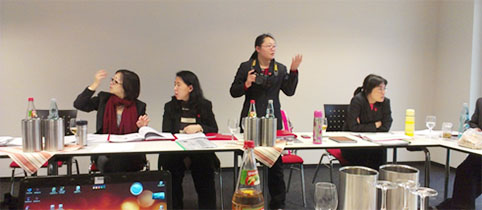 vier Chinesinnen im Schulungsruam, eine spricht stehend