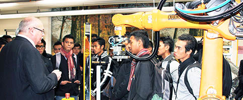 Malaysische Fachkräfte mit einem Mitarbeiter der Eckert Schulen zwischen Maschinen