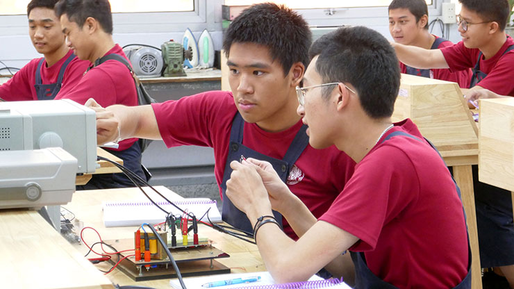 zwei junge Thais arbeiten an einer elektrischen Apparatur