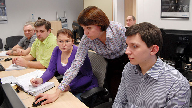 Ausbilderin zeigt mehreren russischen Auszubildenden irgendetwas am Computer