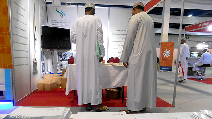 Blick über iMOVE-Flyer auf zwei omanische Besucher