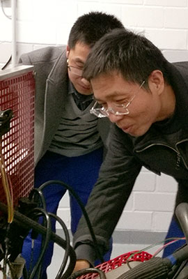 zwei Chinesen beugen sich über eine Apparatur mit Schläuchen