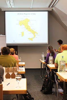 Blick von hinten in den Unterrichtsraum mit einer großen Landkarte der Weinregionen Italiens
