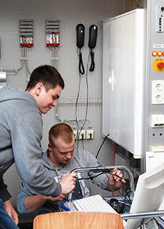 zwei junge Praktikanten arbeiten an Kabeln und Computern